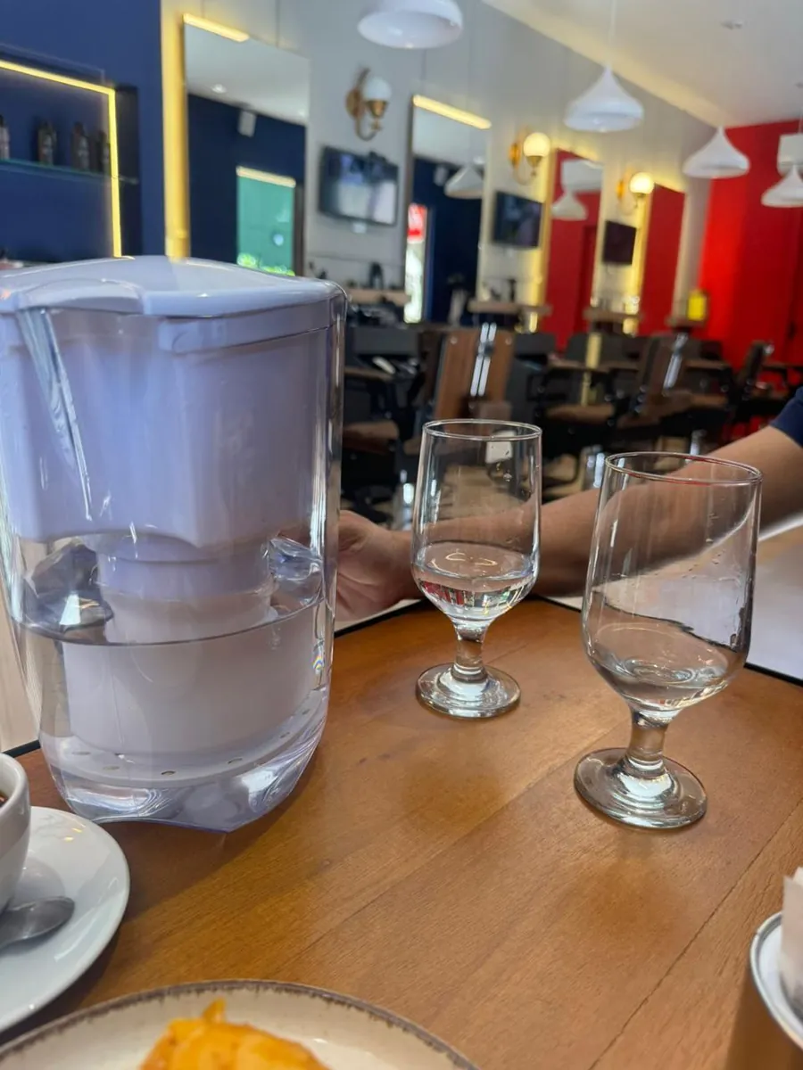 Jarra Alcaline MAX numa mesa, ao lado das taças